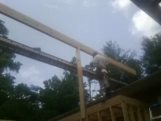 Carpenter setting a ridge beam over a new addition frame — Ice Dam Removal by Roofing Brothers in Felda