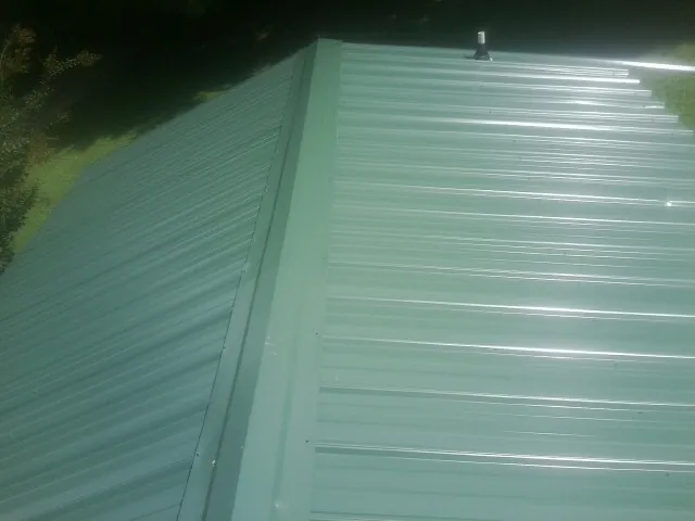 New green metal panels meeting at the ridge of a roof — Flat Roof Repair work by our crew in Felda