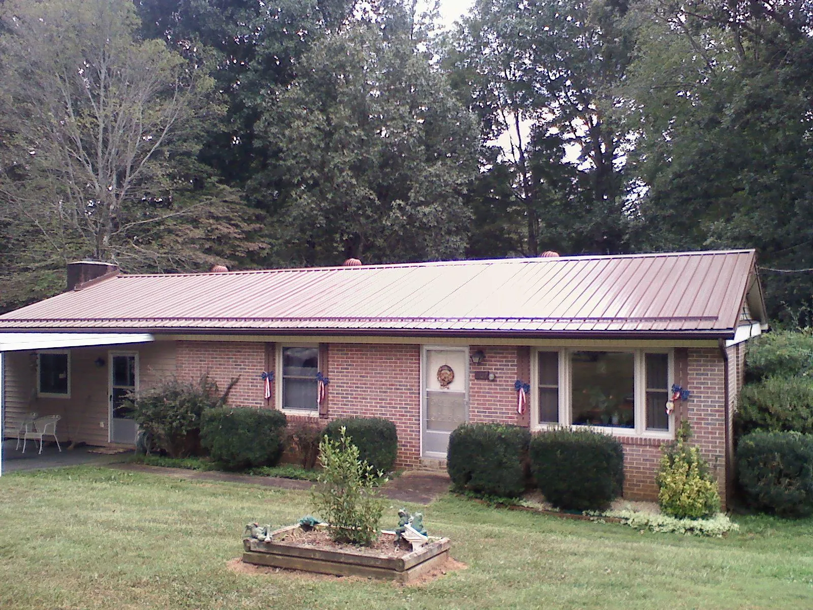 Bronze metal roof on a brick ranch home with a carport in Felda