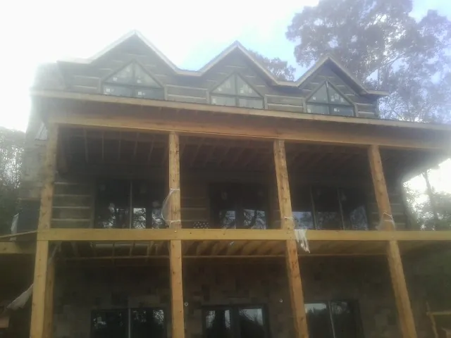 Dormers and porch framing on a large log home under construction — Roof Coating work by our crew in Felda