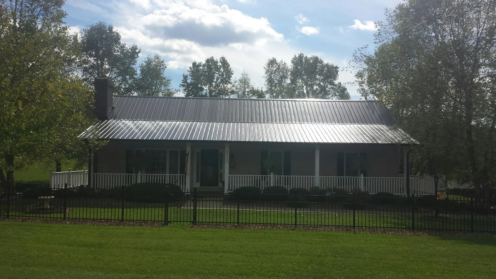 Gray metal roof on a brick ranch with a full width front porch — Gutter Guard Installation work by our crew in Felda