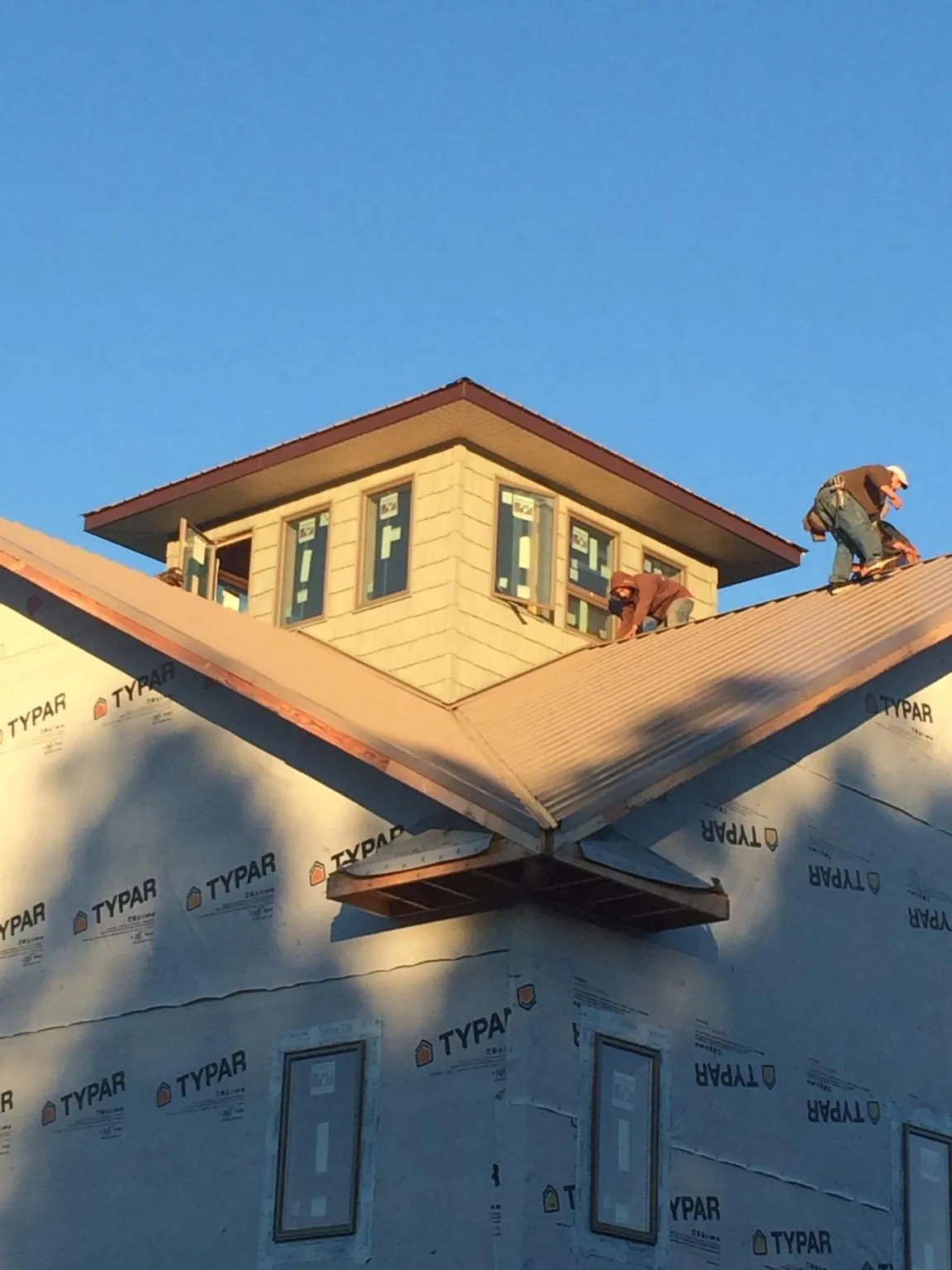 Roofers working around a rooftop cupola on a new metal roof at sunset — Roof Waterproofing in Felda by Roofing Brothers